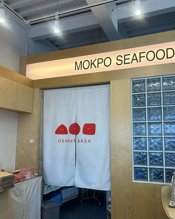 입구 — 「MOKPO SEAFOOD」 간판 + 로고 흰 노렌